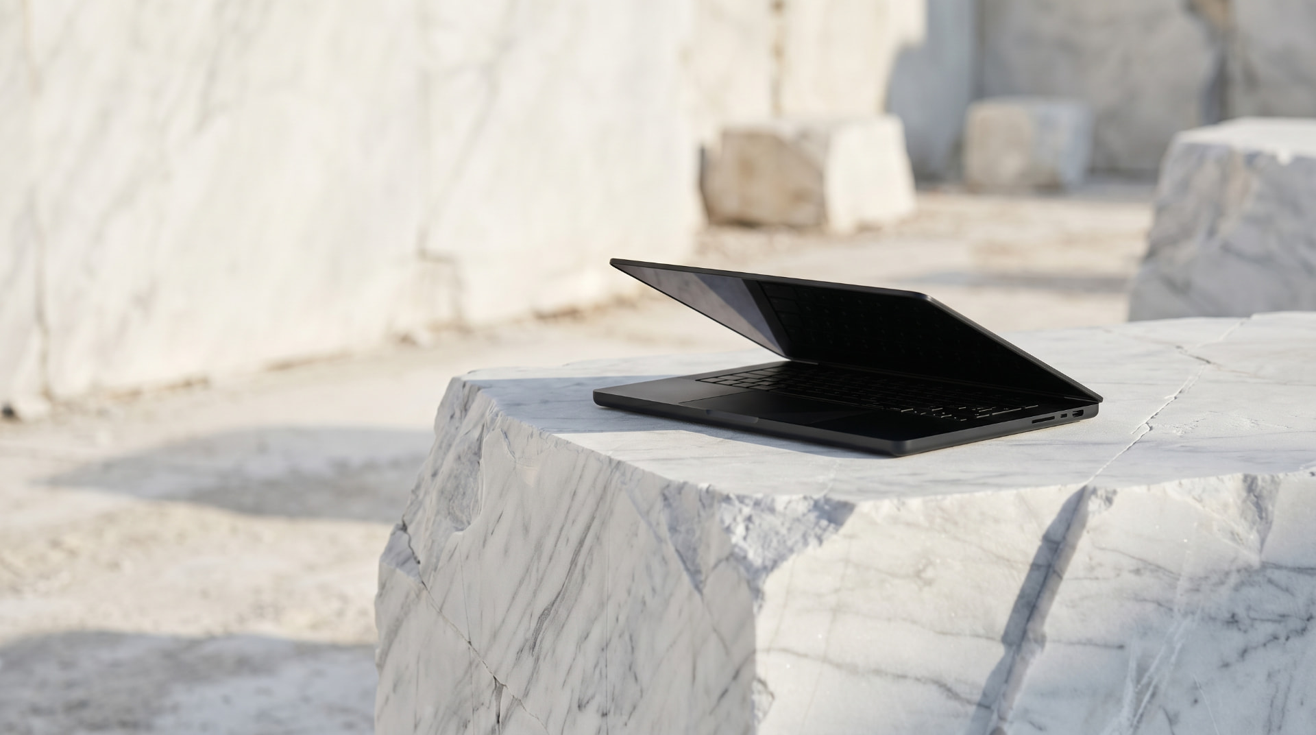 Black laptop open on a block of white marble in a quarry